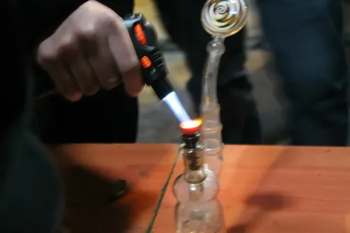 Una mano calienta con un soplete una pipa de vidrio para extractos, Copa Cata del Oeste 2015