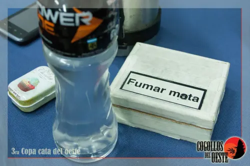 Caja con la leyenda fumar mata, una botella y una latita sobre el mantel, Copa Cata del Oeste 2016
