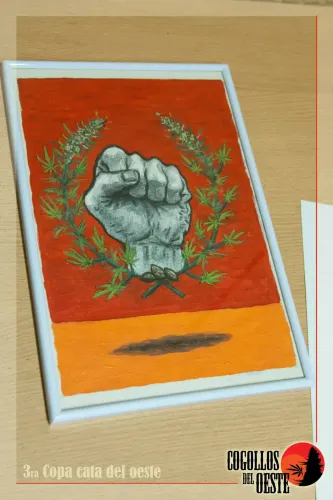 Cuadro pintado con un puño en alto entre ramas de cannabis, sobre una mesa, Copa Cata del Oeste 2016
