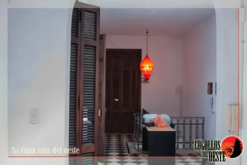 Pasillo del lugar con puertas de madera, una lámpara roja y piso de damero, Copa Cata del Oeste 2016