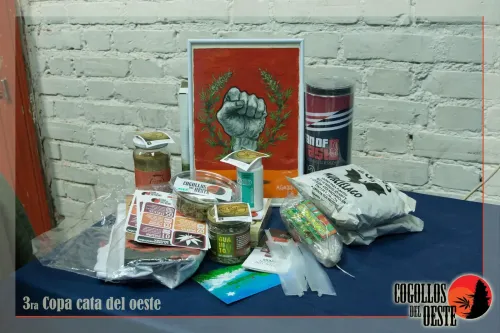 Mesa de premios con un cuadro de un puño en alto y productos de marcas, Copa Cata del Oeste 2016