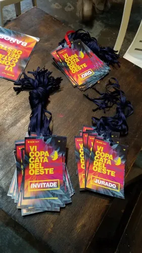 Credenciales de la Copa con cintas para colgar, apiladas sobre una mesa de madera, Copa Cata del Oeste 2019
