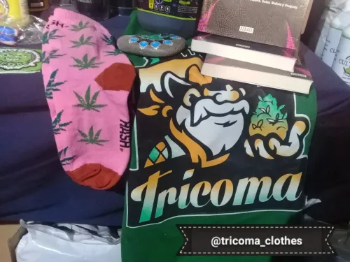 Remera estampada, medias con hojas de cannabis, libros y una piedra pintada en un stand, Copa Cata del Oeste 2019
