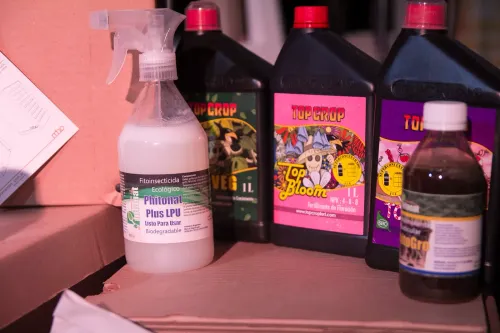Fitoinsecticida con rociador y botellas de fertilizante de varias marcas sobre cajas de cartón, Copa Cata del Oeste 2019