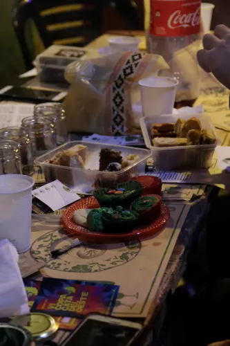 Mesa con frascos vacíos, porciones de budín, budincitos verdes y un folleto de la Copa, Copa Cata del Oeste 2019