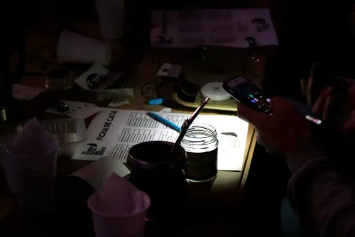 Ficha de cata, mate y frasco de muestra en penumbra, junto a un celular encendido, Copa Cata del Oeste 2019