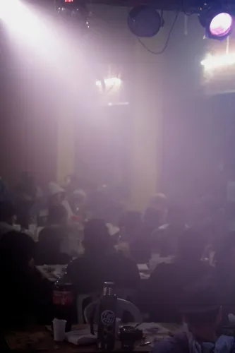 Humo bajo las luces del salón sobre las mesas llenas de gente, Copa Cata del Oeste 2019