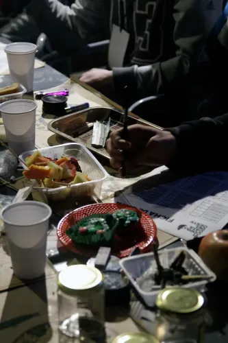 Mesa de cata con fruta, budincitos, vasos, una ficha y una mano con lapicera, Copa Cata del Oeste 2019