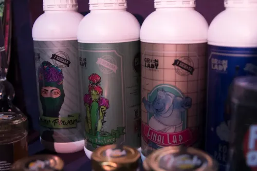 Botellas de fertilizante con etiquetas ilustradas con personajes, detrás de frascos de miel, Copa Cata del Oeste 2019