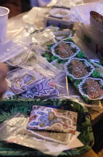 Calcos ilustrados en bolsitas sobre una bandeja con estampado de hojas de cannabis, Copa Cata del Oeste 2019