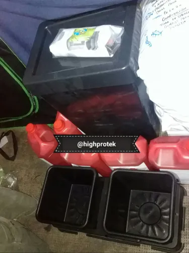 Macetas negras, bidones rojos de fertilizante y una carpa de cultivo en el piso, Copa Cata del Oeste 2019