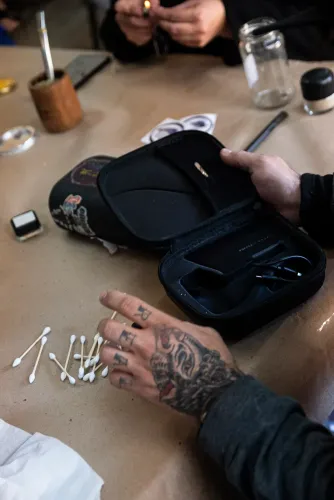 Una mano tatuada ordena hisopos junto al estuche abierto de un vaporizador, Copa Cata del Oeste 2022