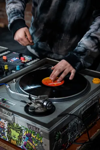 Una mano detiene un disco de vinilo en la bandeja giradiscos del DJ, Copa Cata del Oeste 2022