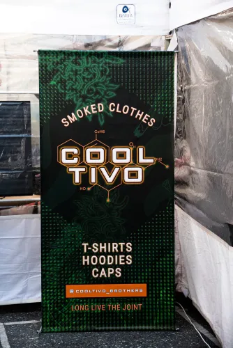 Banner de una marca de ropa cannábica junto a la carpa de un stand, Copa Cata del Oeste 2022