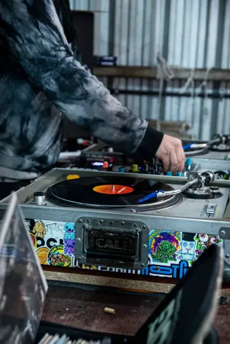 Bandeja giradiscos sobre un estuche lleno de stickers y el brazo del DJ, Copa Cata del Oeste 2022
