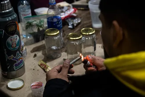 Manos encienden un porro entre frascos de muestras vacíos y un termo con stickers, Copa Cata del Oeste 2022