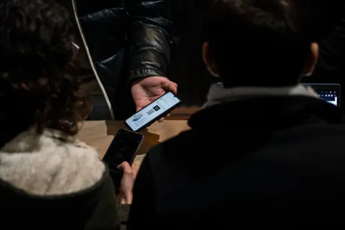 Dos personas de espaldas muestran en el celular el código QR de la acreditación, Copa Cata del Oeste 2022
