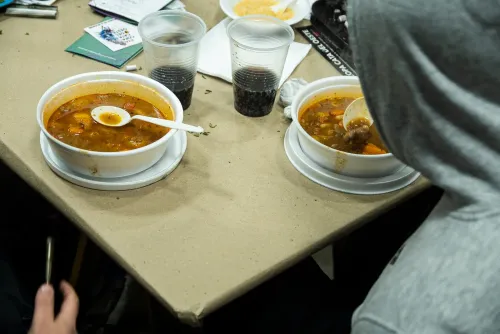 Platos de guiso y vasos sobre la mesa mientras dos personas almuerzan, Copa Cata del Oeste 2022