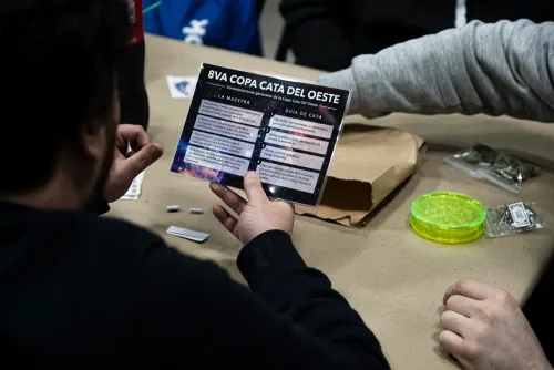 Una persona de espaldas lee la guía de cata plastificada en la mesa, Copa Cata del Oeste 2022