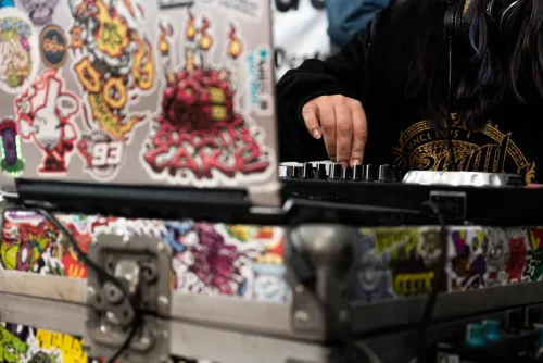 Notebook cubierta de stickers y una mano sobre el controlador de DJ, Copa Cata del Oeste 2022