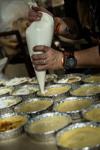 Manos con una manga pastelera decoran tartas en moldes de aluminio para el postre, Copa Cata del Oeste 2022