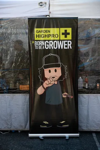 Roll-up de una marca de cultivo con un personaje dibujado frente a un stand, Copa Cata del Oeste 2022